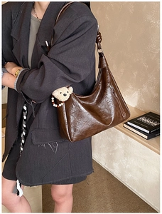 Dettaglio della borsa tote in pelle lucida marrone scuro con ciondolo a forma di orsetto