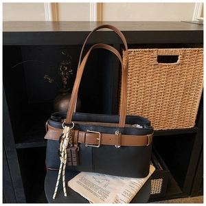 Détail du sac cabas rétro noir avec lanières en cuir marron et boucle métallique