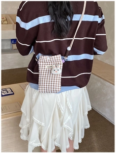 Petit sac à bandoulière à carreaux marron avec charme de lapin porté par un modèle