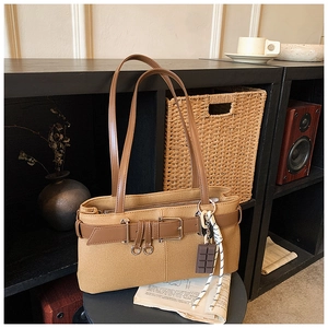 Détail du sac à bandoulière en toile kaki avec lanières en cuir brun et pendentif chocolat