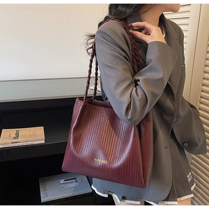Detailed view of woven texture and gold Tote Bag lettering on burgundy shoulder bag