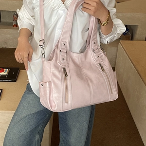Détail latéral d'un grand sac cabas en cuir rose clair avec fermetures éclair
