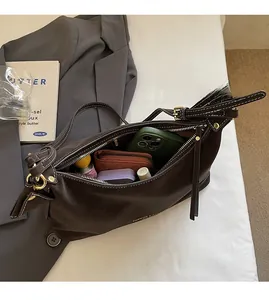 Intérieur spacieux du sac en cuir marron foncé montrant le rangement du téléphone et du portefeuille