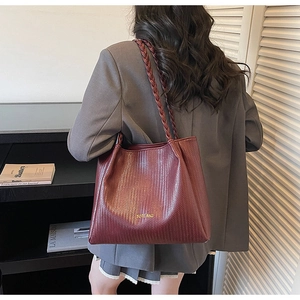 Detail of burgundy woven texture tote bag featuring a small golden TOTE BAG logo on leather