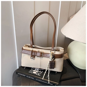 Détail du sac à main en toile rétro avec finitions en cuir et pendentif chocolat