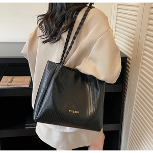 Close-up of black woven textured tote bag with gold lettering and rope handles