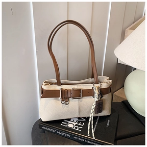 Détail du sac cabas en toile beige avec bandoulière en cuir marron et pendentif