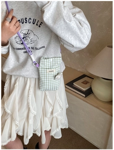 Vue détaillée d'une mini sacoche vichy verte avec breloque lapin et étiquette de marque