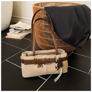 Détail d'un sac à bandoulière en toile beige rétro avec brides en cuir et breloques de mode