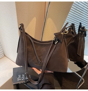 Vue détaillée du sac en daim marron foncé avec logo doré et boucles métalliques