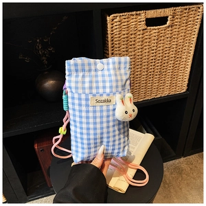 Détail d'un sac à téléphone à carreaux bleus avec pendentif lapin et sangle rose