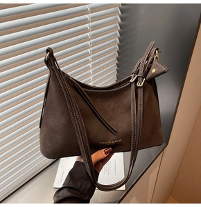Détail du sac à bandoulière en cuir café foncé avec boucles dorées et mini pochette