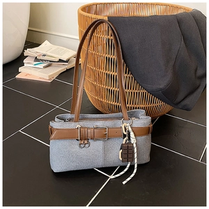 Détail du sac sous le bras en denim avec boucle de ceinture en cuir et pendentif chocolat
