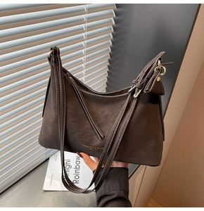 Détail du sac en cuir marron avec surpiqûres blanches et marquage doré élégant