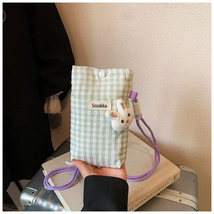 Détail du petit sac à damier vert avec breloque lapin et bandoulière violette