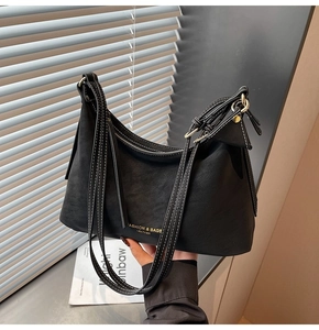 Détail du sac à main en cuir noir mat avec coutures blanches et logo doré