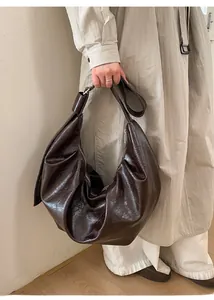 Détail du sac fourre-tout en cuir ciré marron foncé avec texture plissée et zip argenté