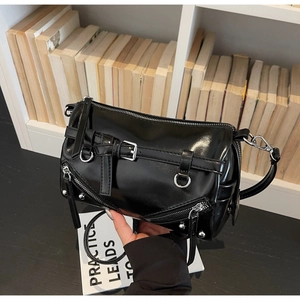 Detail of black glossy cylindrical shoulder bag with silver buckles and punk studs