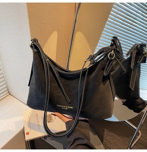 Détail d'un sac en cuir noir avec lettrage doré et boucle métallique de la bandoulière