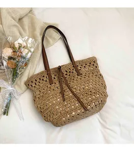 Detail of hollow-out straw weave texture and brown leather strap on oversized beach tote