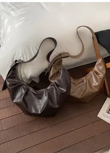Détail de sacs demi-lune en similicuir souple aux couleurs marron foncé et caramel
