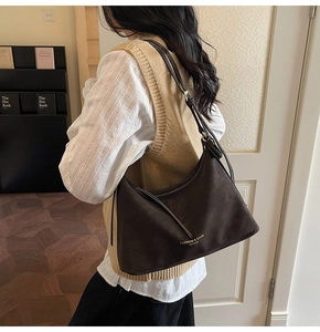 Vue détaillée du sac à bandoulière en cuir marron foncé porté dans un décor épuré