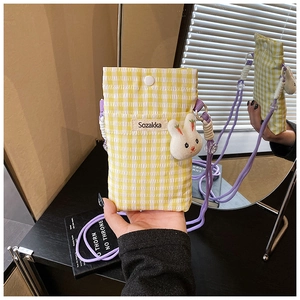 Détail du sac bandoulière à carreaux jaunes avec sangle violette et lapin peluche