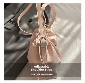 Detailed close-up of the adjustable strap and metal buckle on the pink bucket bag