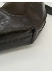 Gros plan détaillé montrant la texture mate douce et le grain fin du sac en cuir brun