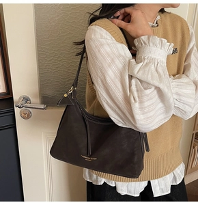 Détail du sac hobo en cuir marron foncé avec bandoulière réglable et logo doré