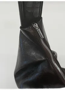 Détail de la texture cuir ciré et de la fermeture éclair en métal argenté du sac