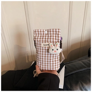 Vue détaillée du sac bandoulière à carreaux avec bouton et breloque lapin en peluche