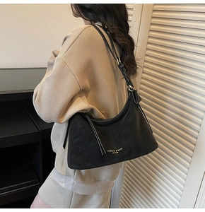 Détail du sac hobo noir avec des coutures contrastées blanches et texte doré élégant