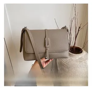 Close-up of taupe textured leather crossbody bag featuring silver metal buckle and strap