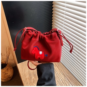 Detail showing the red drawstring bucket bag with horse embroidery and metal buckle