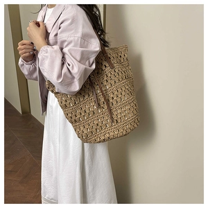 Close-up of woven straw tote bag with brown leather straps for spring beach vacations