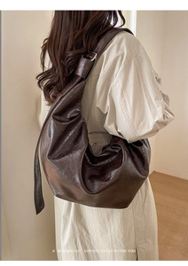 Vue macro du sac croissant en cuir huilé marron foncé minimaliste avec texture froissée