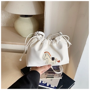 Detail of white leather drawstring bucket bag featuring a 3D pony embroidery and thin strap