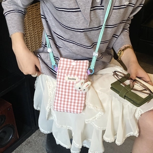 Sacoche de téléphone rose à carreaux avec breloque lapin en peluche porté par mannequin