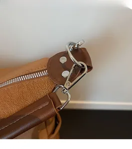Détails de la mercerie argentée et du cuir marron texturé d'un grand sac bandoulière