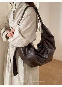 Détail du sac croissant en cuir ciré marron foncé montrant coutures et texture