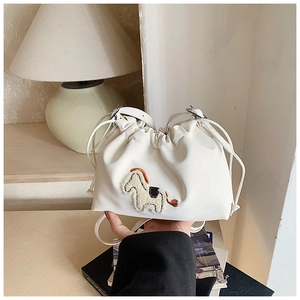 Detailed view of white drawstring bucket bag featuring 3D pony embroidery and leather strap