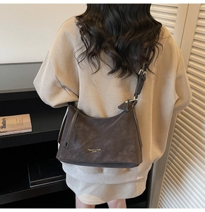 Détail du sac à bandoulière en daim taupe foncé avec texte doré et bandoulière réglable