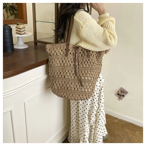 Detail of the woven straw tote bag with brown leather straps and texture closeup