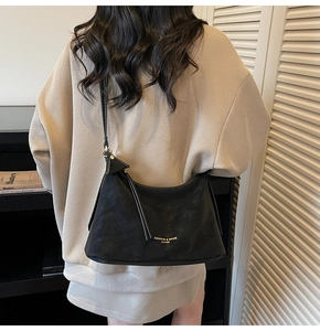Détail du sac bandoulière demi-lune en cuir noir mat avec logo doré imprimé dessus
