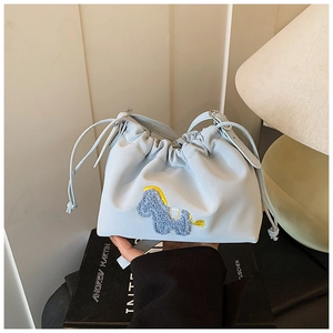 Detailed view of light blue drawstring bucket bag featuring a cute donkey embroidery