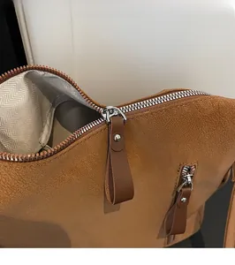 Détail de la fermeture éclair argentée et de la tirette en cuir marron sur le sac à bandoulière