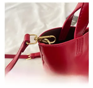 Dettaglio ravvicinato di borsa tote in pelle rossa con finiture in metallo oro