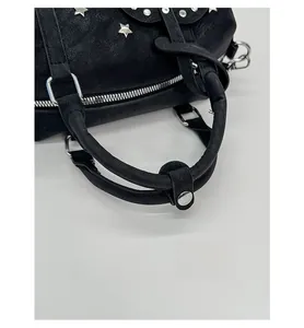 Detailaufnahme der schwarzen Handtasche mit Sternnieten und Druckknopf am Tragegriff