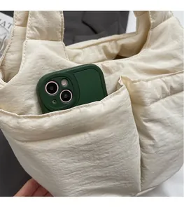 Macro shot of off-white quilted nylon bag showing deep pocket with smartphone inside